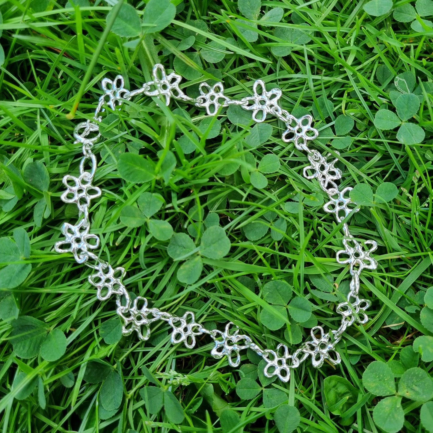 Silver flower chain necklace on a grass background