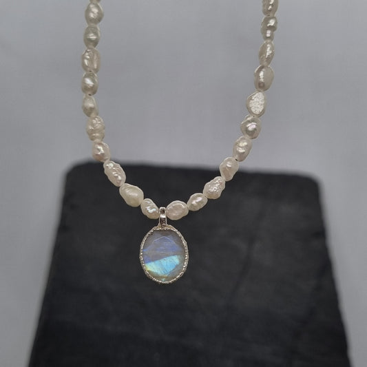 Pearl necklace with an oval-shaped moonstone gemstone pendant on a grey background