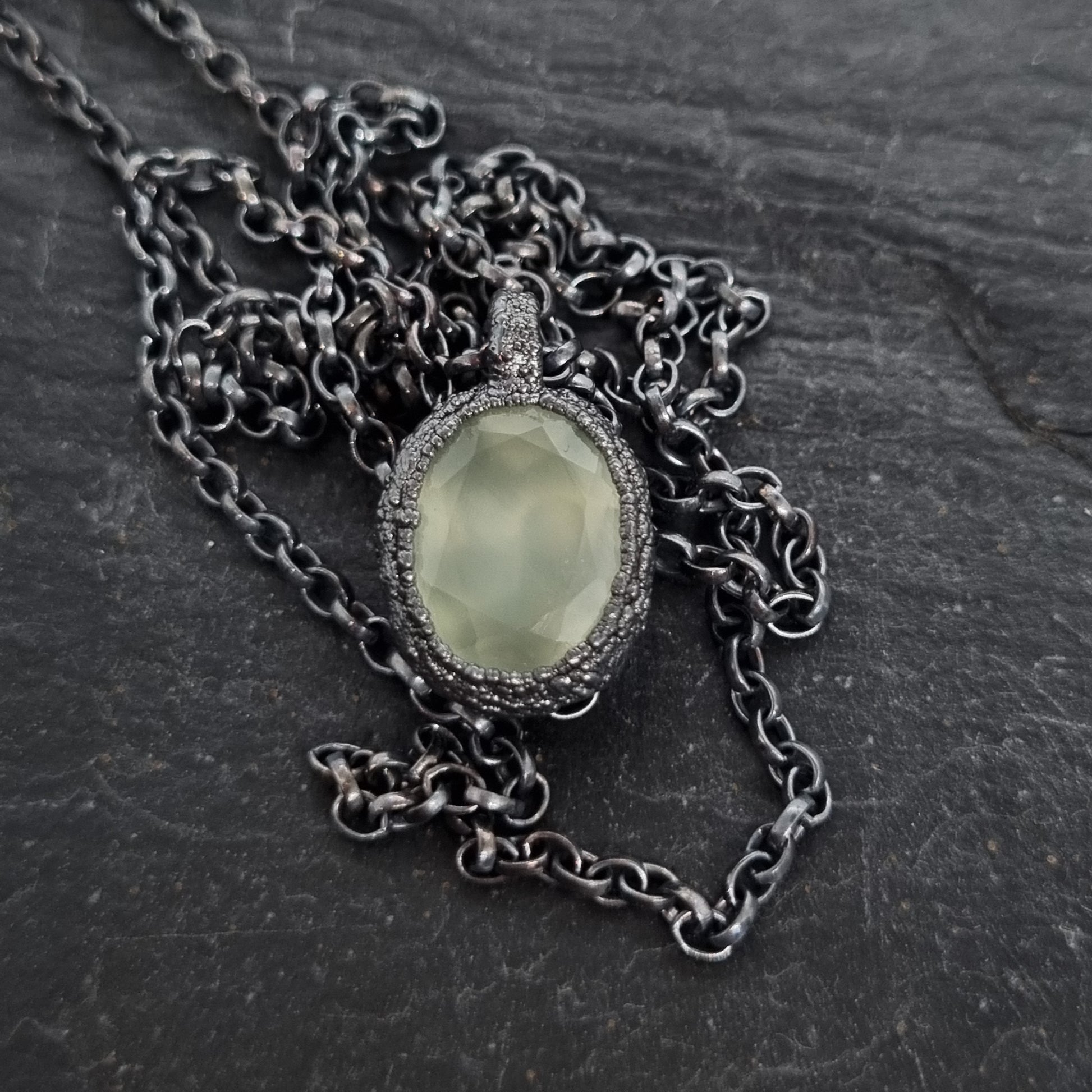 Necklace with a green stone pendant on a dark textured surface