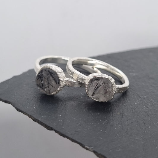 two raw black tourmalated quartz sterling silver rings displayed on slate