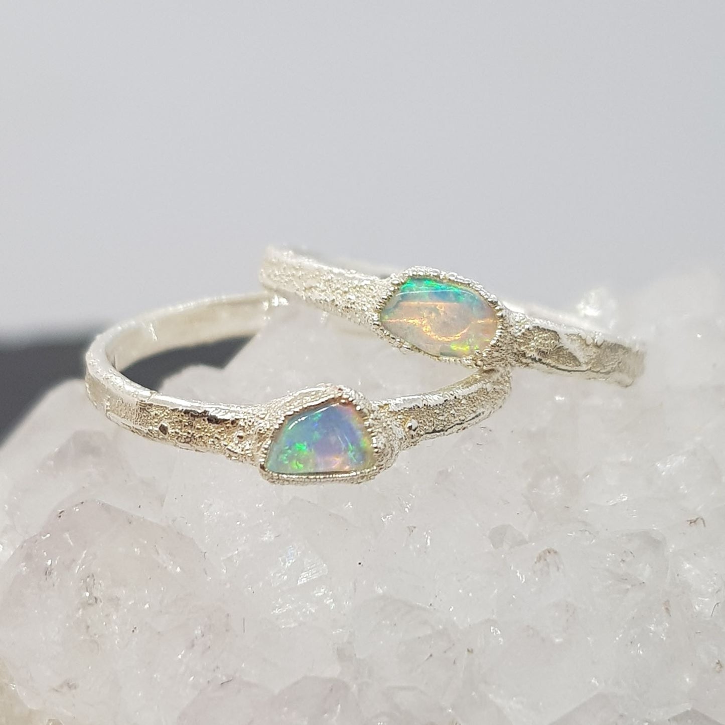 raw opal textured silver rings displayed on a crystal