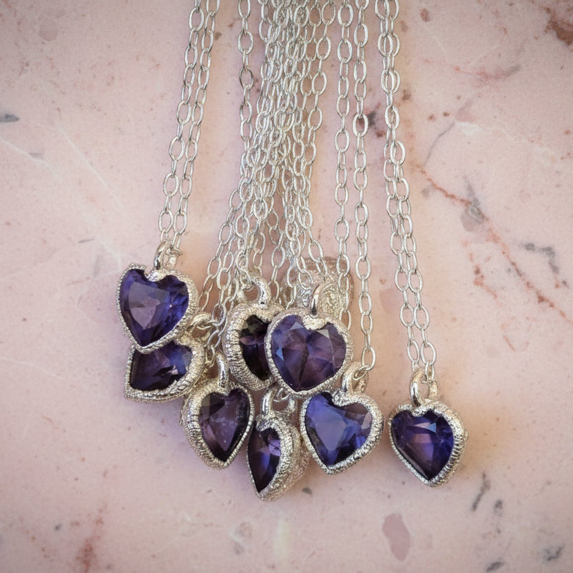 Set of heart-shaped purple gemstone necklaces on a marble surface