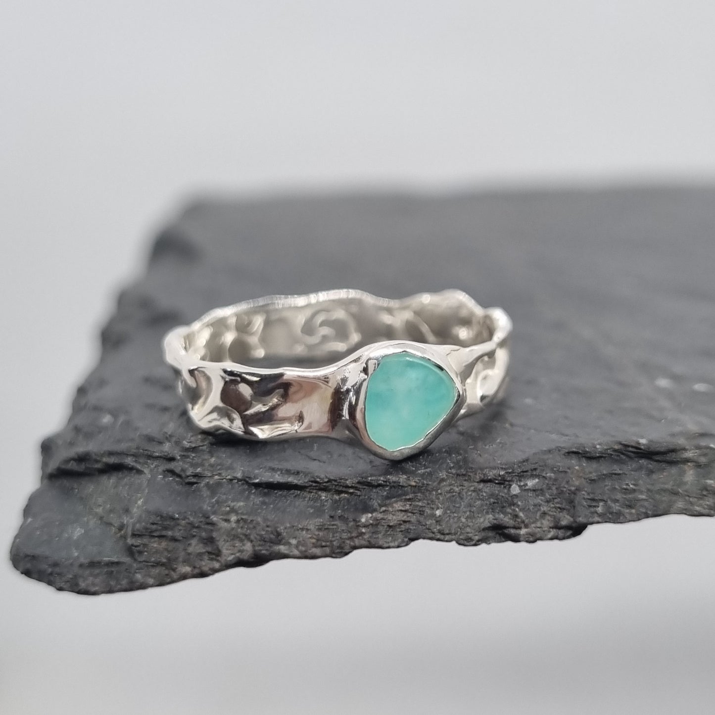 Handmade sterling silver ring with an amazonite gemstone on a dark stone surface