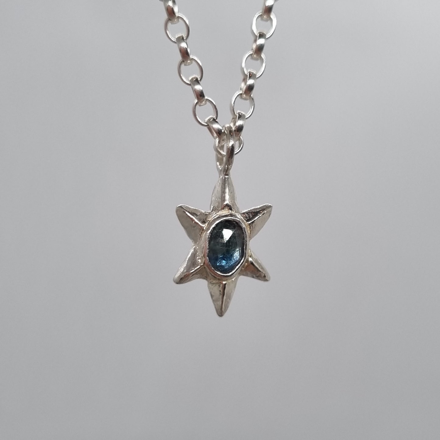 rose cut teal blue sapphire set in hand carved sterling silver faceted star pendant. Comes on a long sterling silver chain handmade by Jo Cooper Jewellery