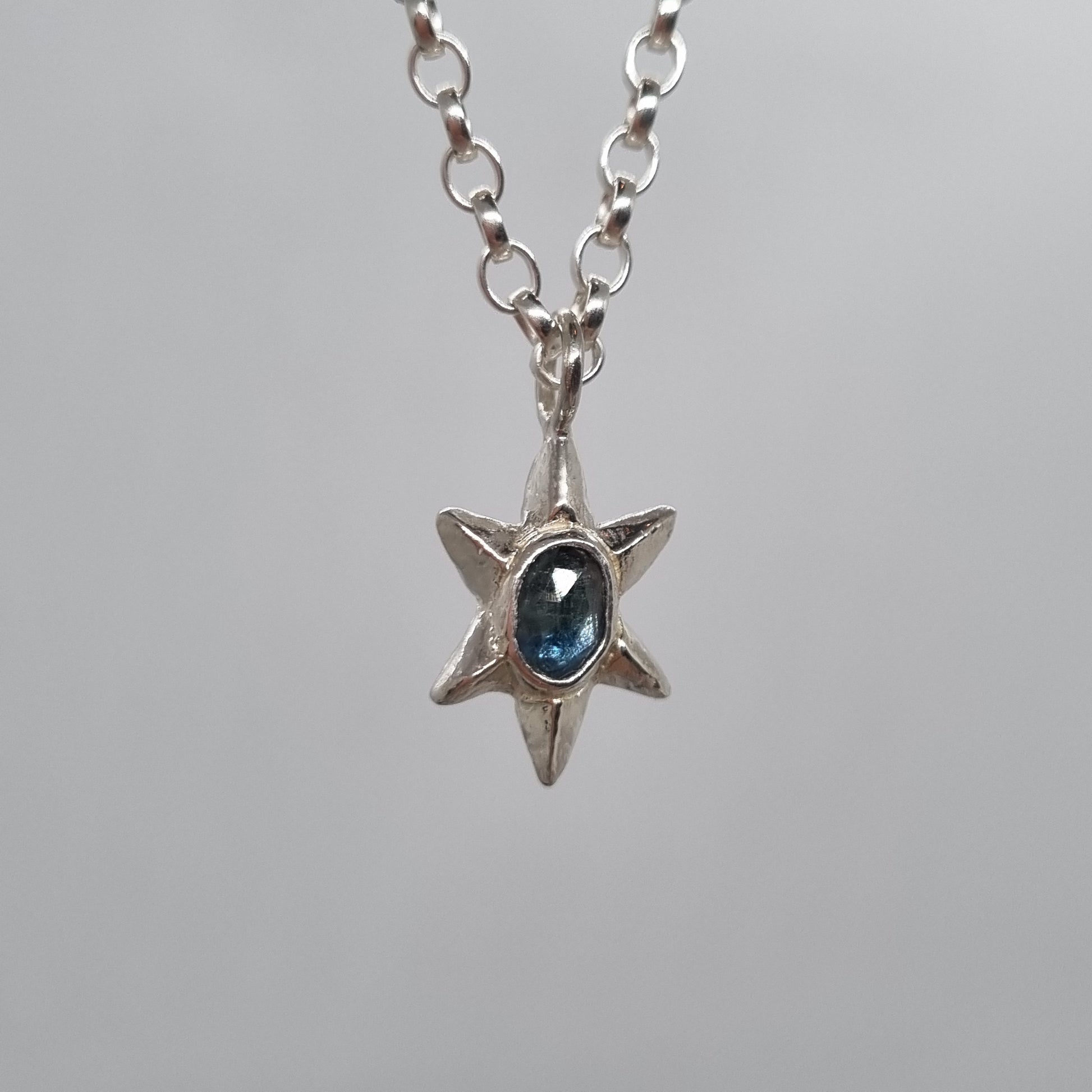 rose cut teal blue sapphire set in hand carved sterling silver faceted star pendant. Comes on a long sterling silver chain handmade by Jo Cooper Jewellery