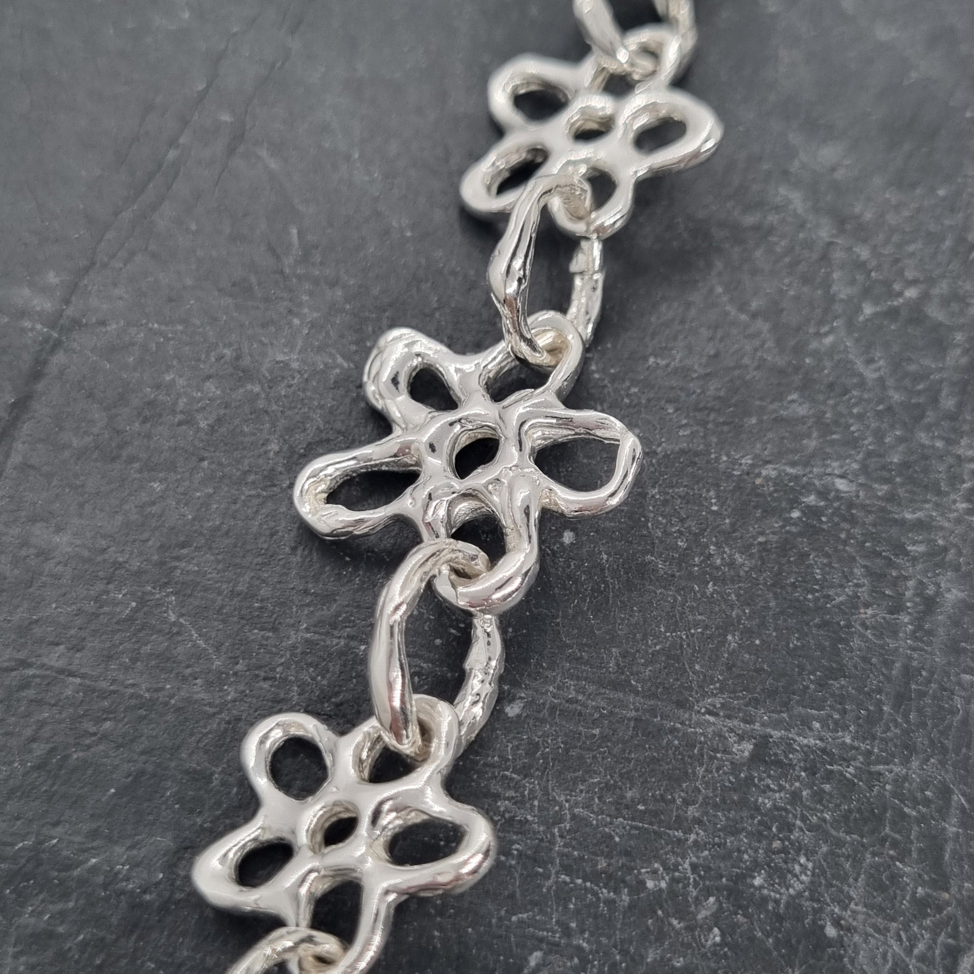 Chunky sterling silver flower chain necklace on a dark grey background