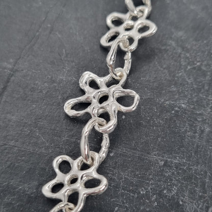 Chunky sterling silver flower chain necklace on a dark grey background