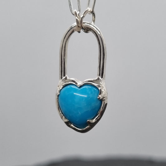 Turquoise heart-shaped pendant on a silver chain against a grey background