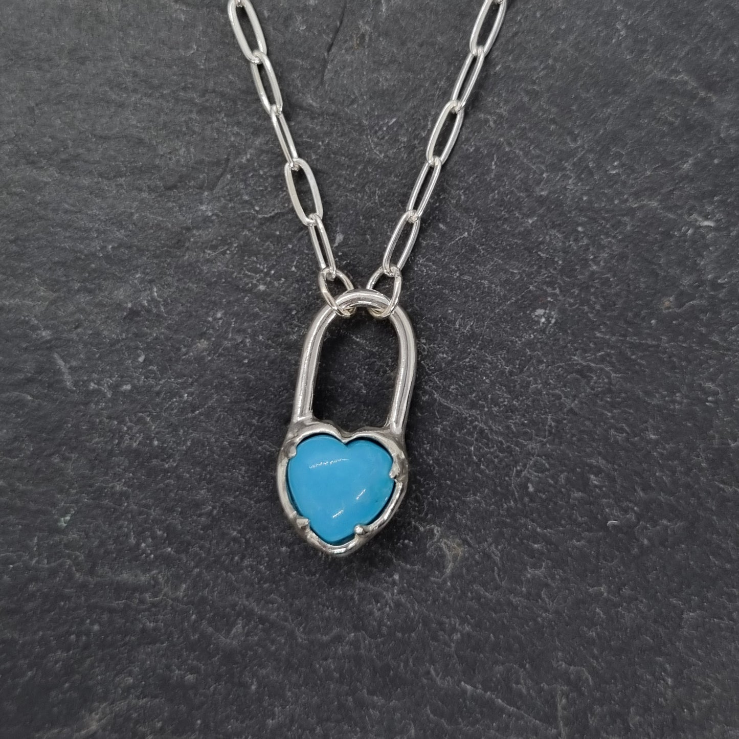 Sterling silver necklace with a turquoise heart pendant on a dark gray background