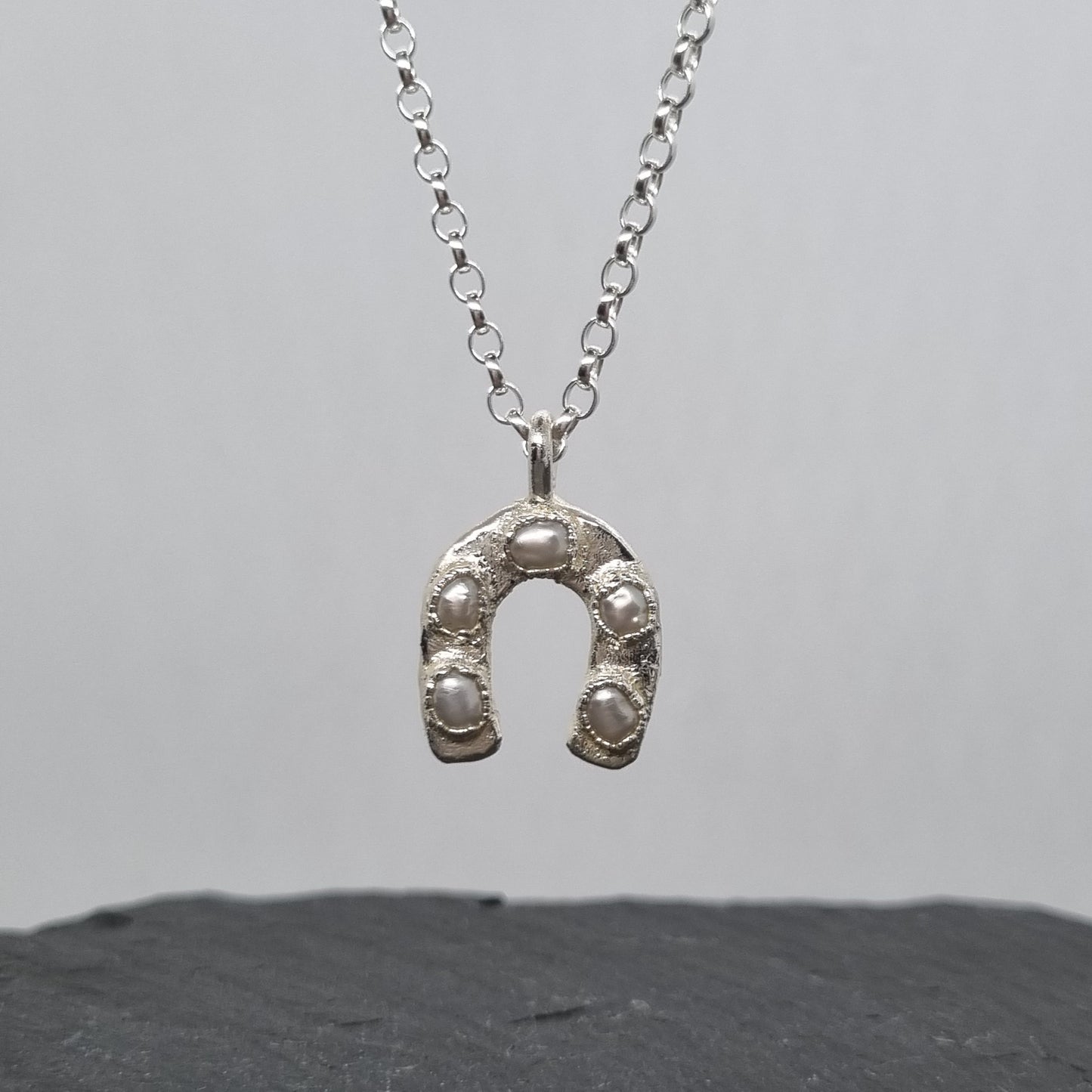 Handmade sterling Silver horseshoe necklace on a gray background by Jo Cooper Jewellery