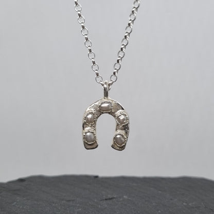 Handmade sterling Silver horseshoe necklace on a gray background by Jo Cooper Jewellery