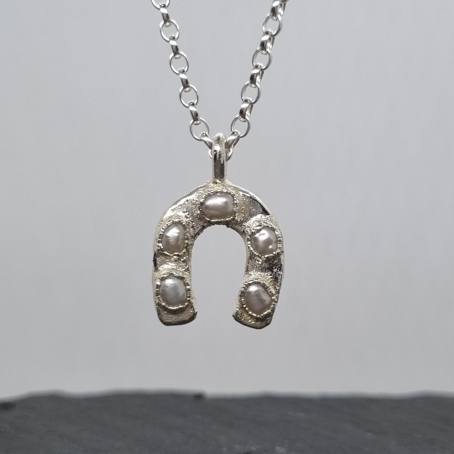 Sterling silver and 5 freeform pearls horseshoe pendant necklace on a light grey background