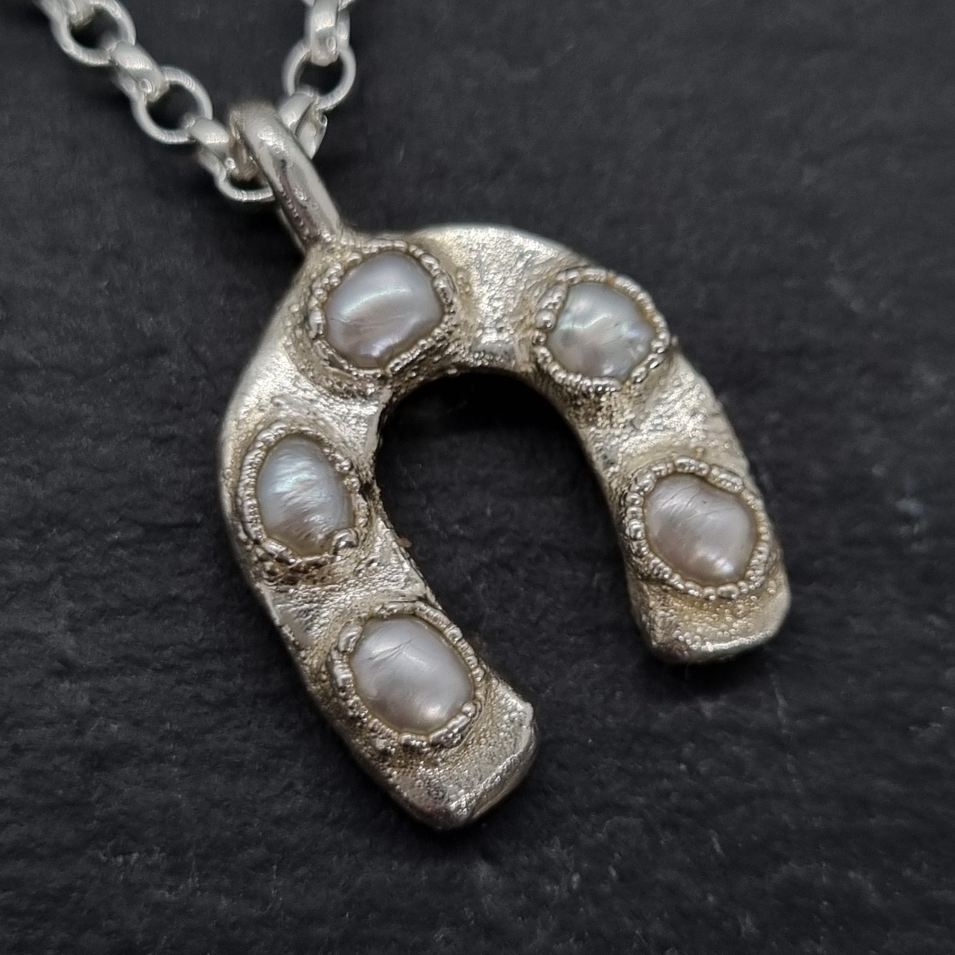 Silver horseshoe pendant with embedded freshwater pearls. Lunar New Year of the Horse