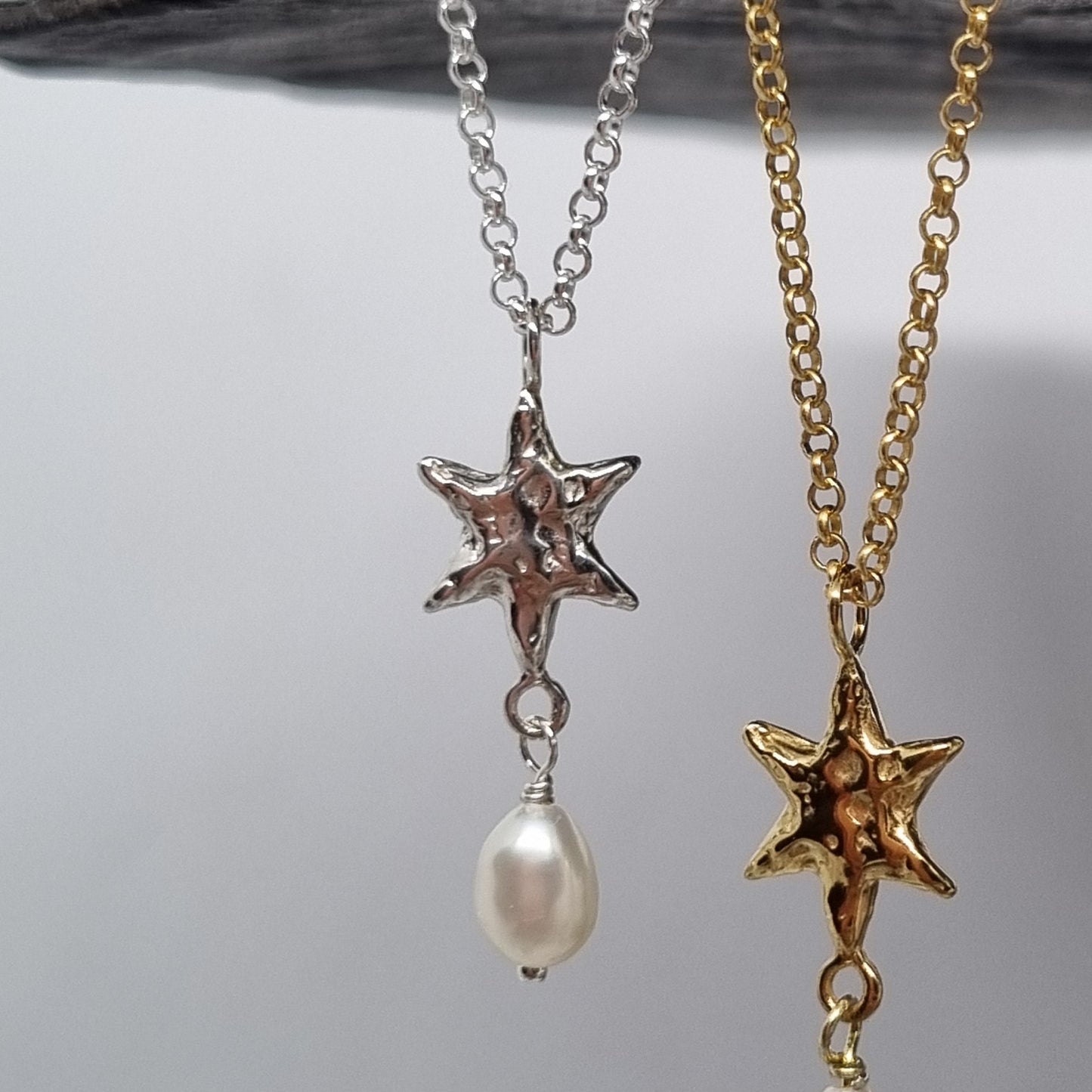 Gold and silver star-shaped earrings with pearls on a gray background