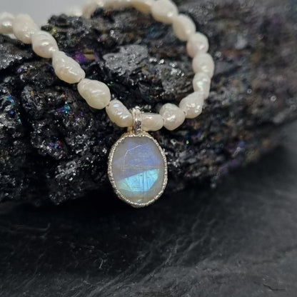 sterling silver pearl necklace with a rainbow moonstone pendant on a dark stone background