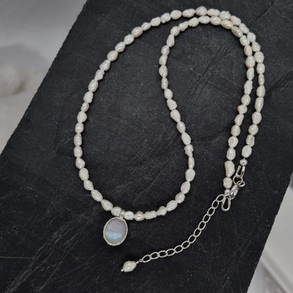 Pearl and moonstone necklace with a silver clasp on a dark surface