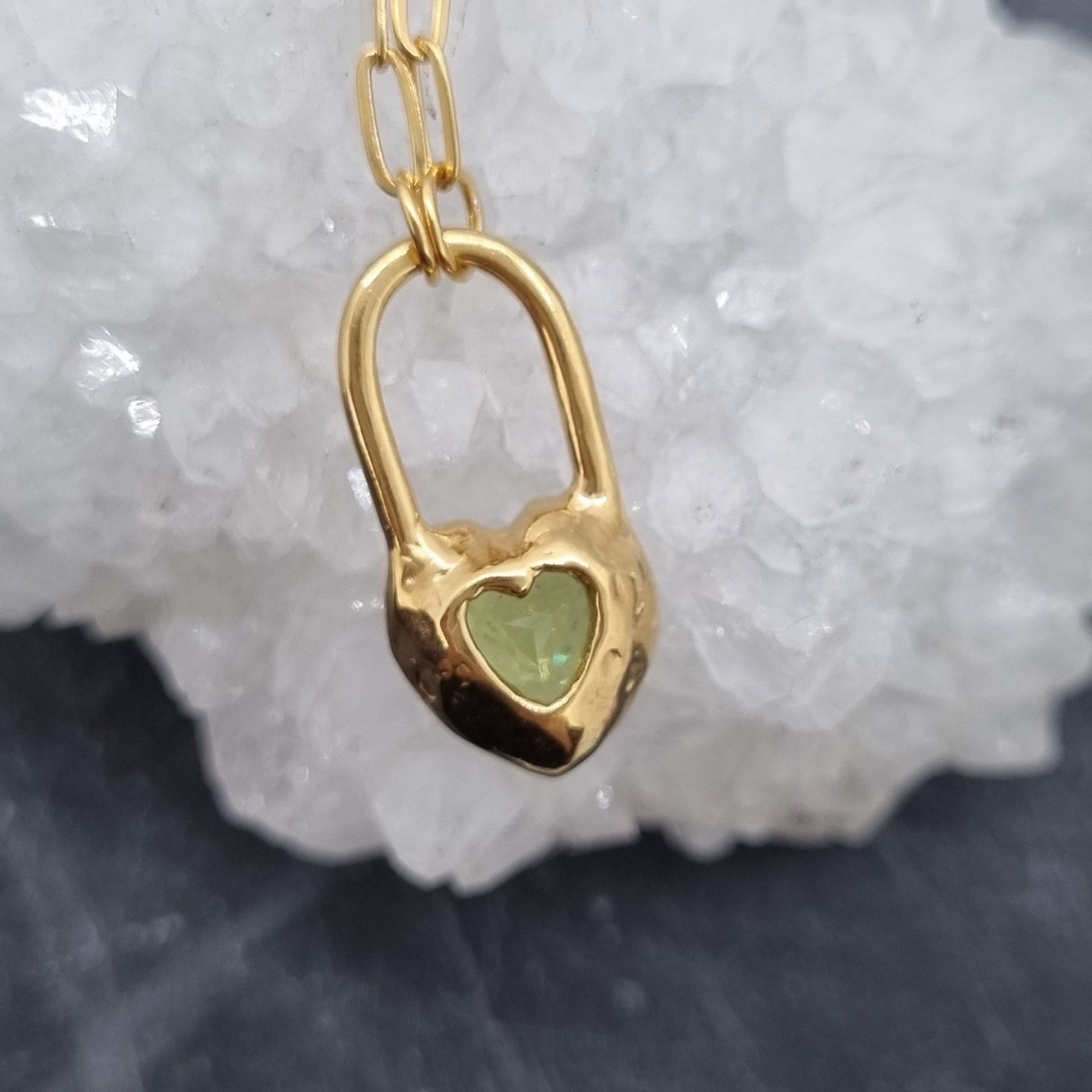 Gold vermeil necklace with a green gemstone pendant on a white stone background