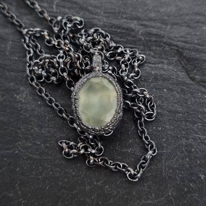 Necklace with a green stone pendant on a dark textured surface