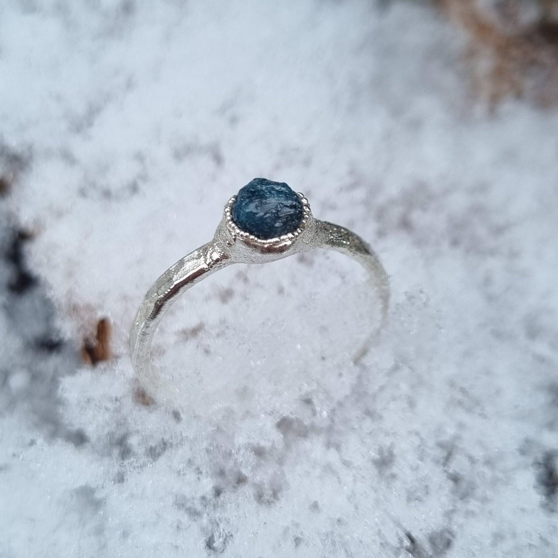 natural raw blue diamond sterling silver textured ring displayed in the snow