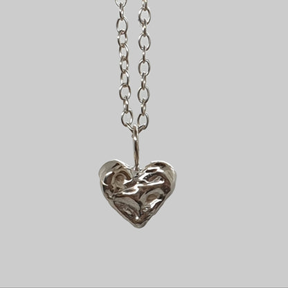 Gold and silver heart-shaped pendants on chains against a light gray background