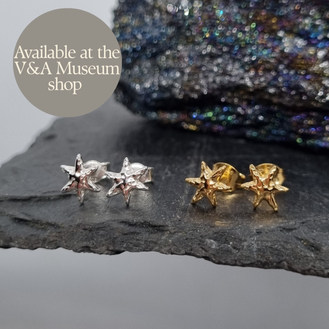 Pair of sterling silver and gold plated star shaped stud earrings on a dark stone surface. Handmade by Jo Cooper. Also available at the Victoria and Albert Museum shop in London, UK.