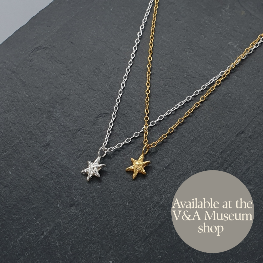 tiny textured star necklaces in sterling silver and gold plated silver on a dark grey slate. Handmade by Jo Cooper. Also available at the V&A Museum shop in London, UK.
