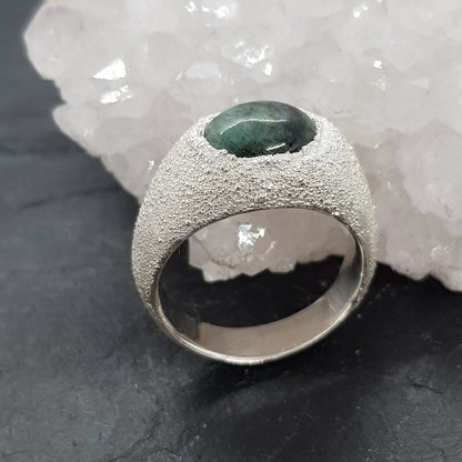 raw emerald matrix textured silver signet ring next to crystal