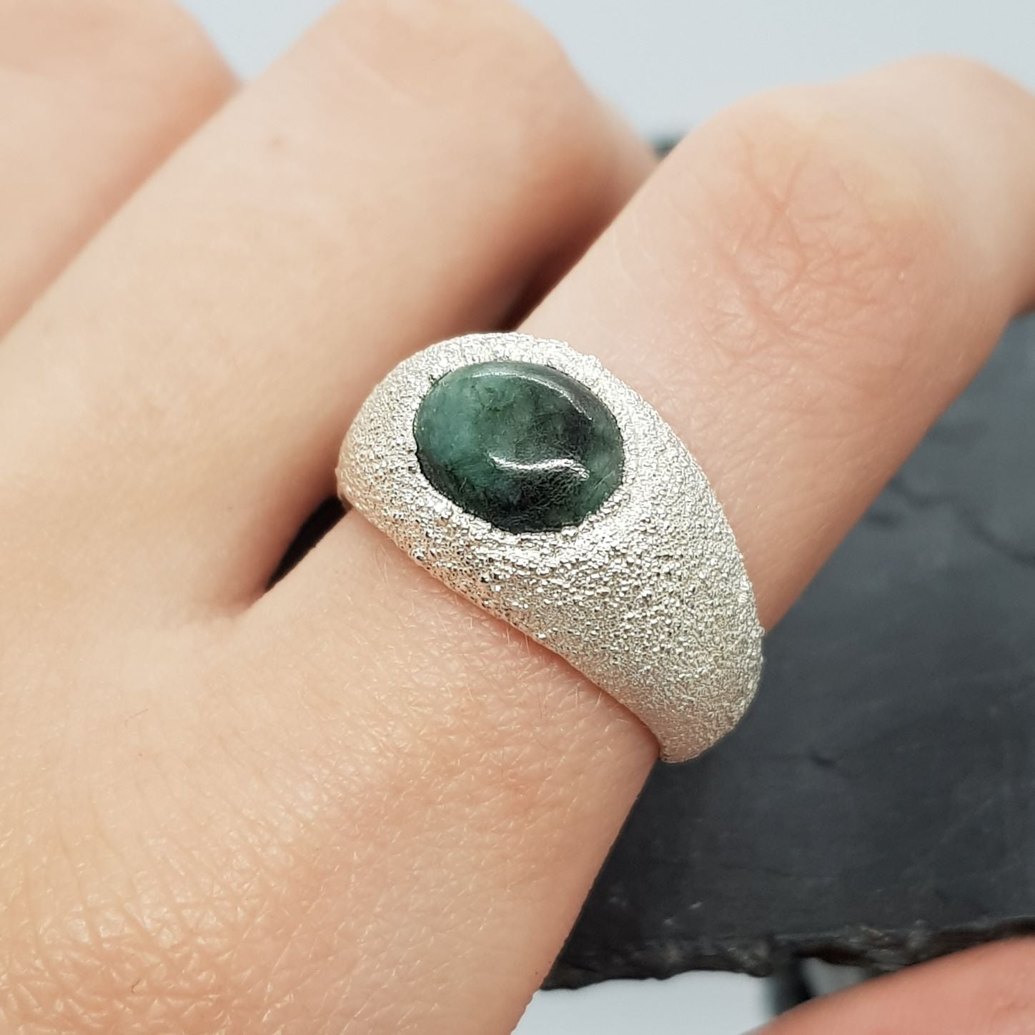 raw emerald matrix textured silver signet ring on finger