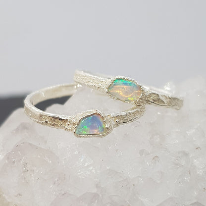 raw opal textured silver rings displayed on a crystal