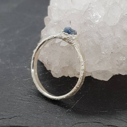 raw uncut blue sapphire ring displayed on slate