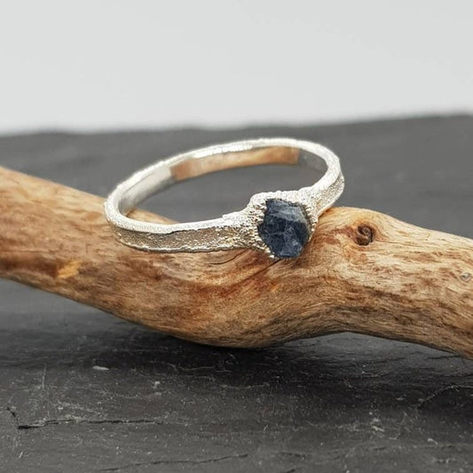 raw uncut blue sapphire ring displayed on slate