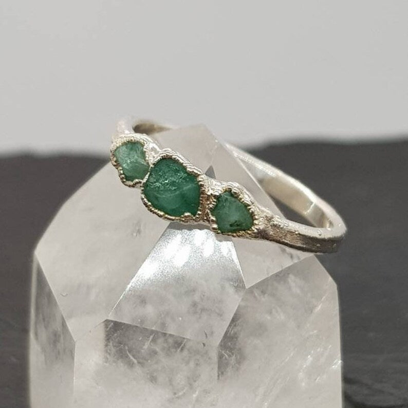 triple raw emerald silver ring displayed on a crystal