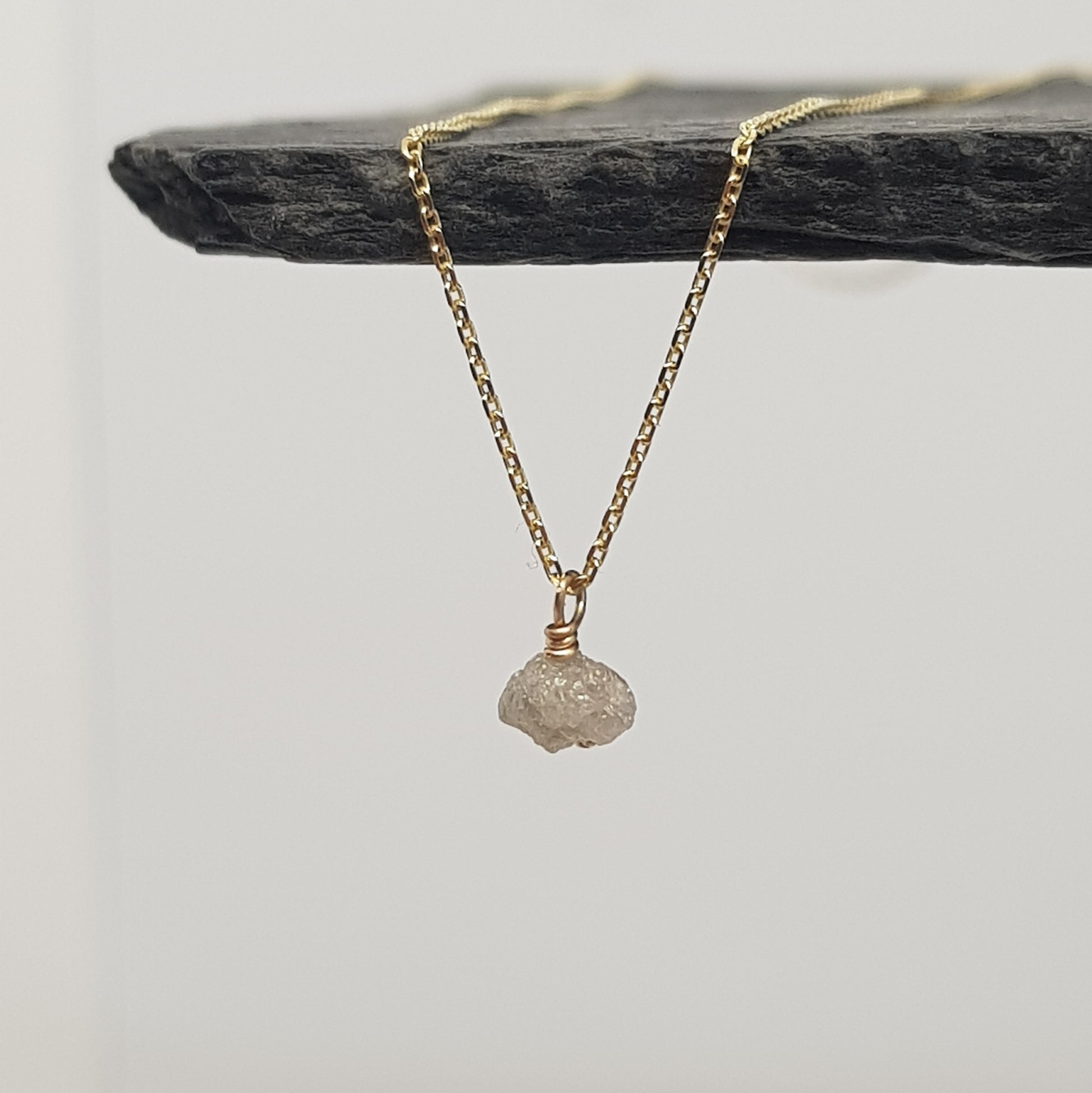 raw white diamond necklace on 9ct yellow gold chain, displayed hanging from a black slate